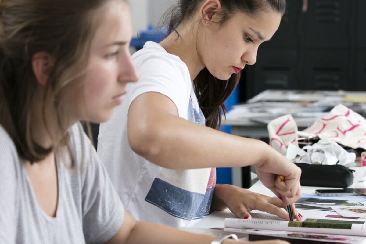Two people working with paper and materials at a shared table.