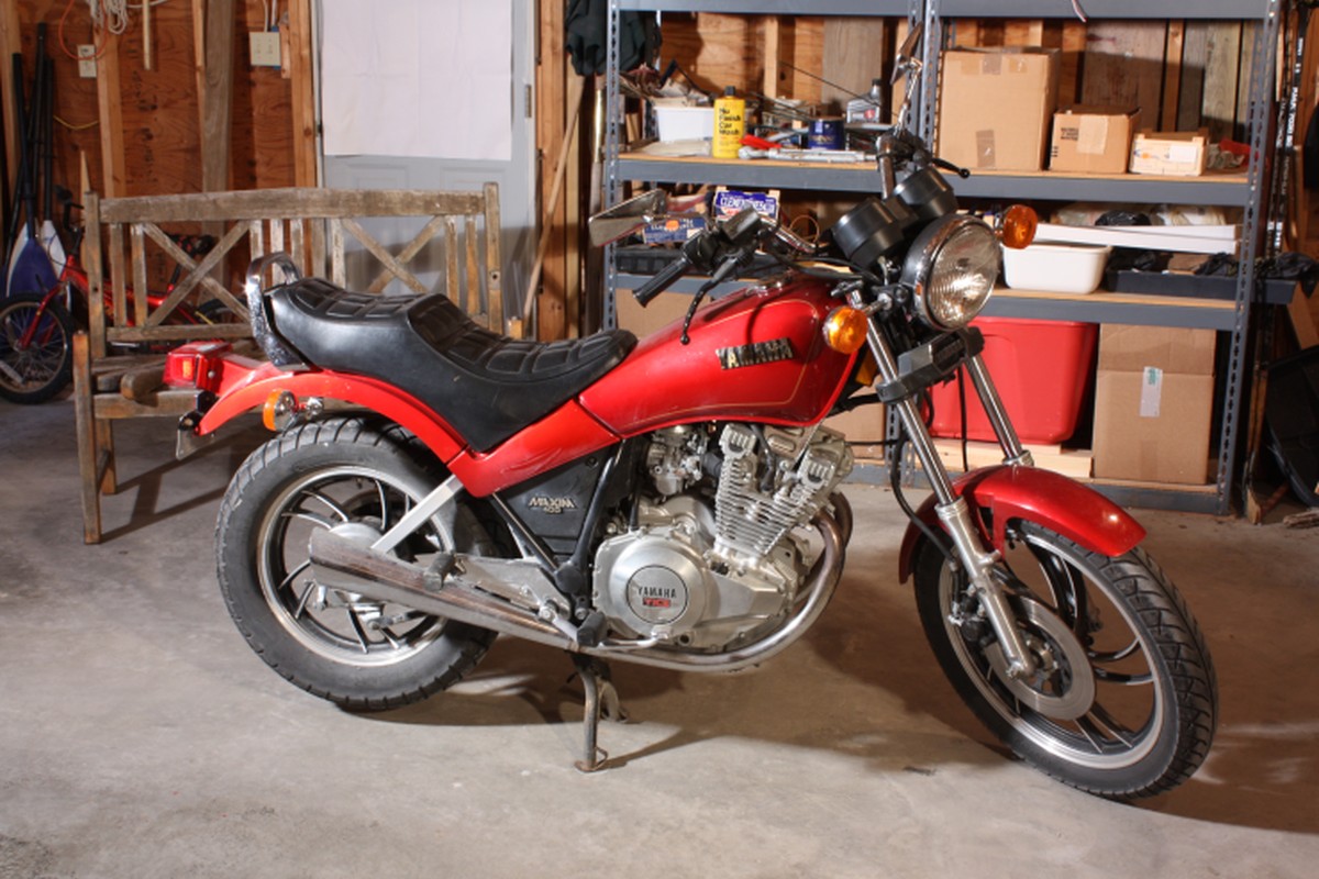 A red motorcycle parked indoors beside workshop objects.